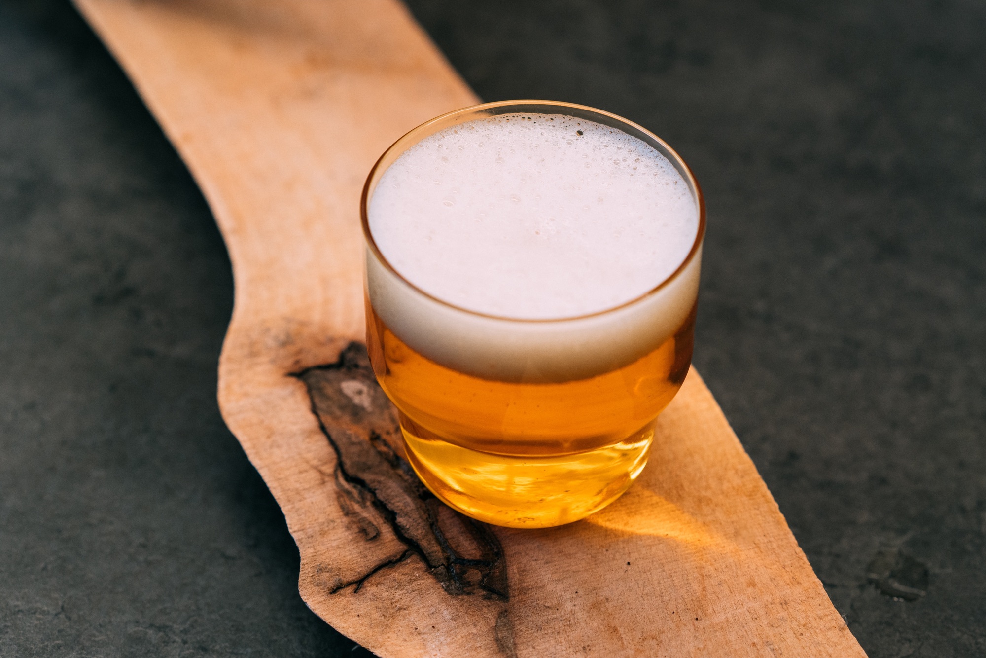 Handgemachtes Craft-Bier mit dichter Schaumkrone in einem Glas auf einem Holzbrett